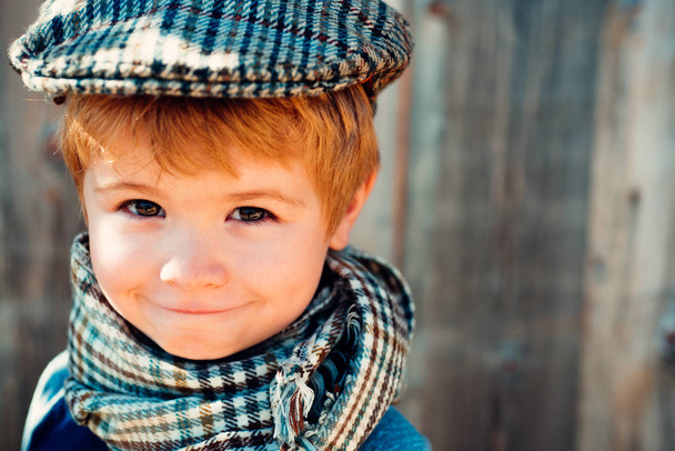 Дитяча мода. Хлопчик у старовинній шапці. Стара школа. Усміхнена дитина. Прекрасний плакат на дерев'яному фоні
 - Фото, зображення