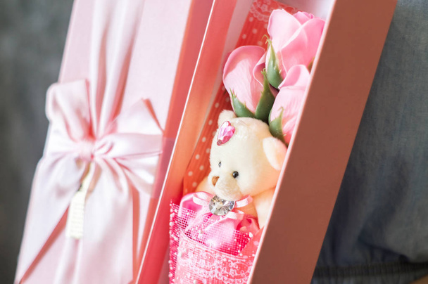 Florists work: A girl demonstrates a box with a bouquet of pink roses and a teddy bear. - Photo, Image