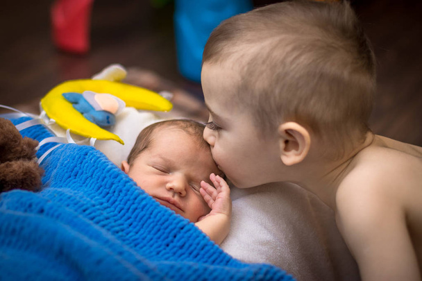 брат два старых года целует новорожденного ребенка
. - Фото, изображение