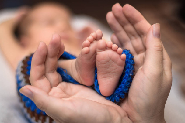 Родитель держит в руках ноги новорожденного ребенка. - Фото, изображение