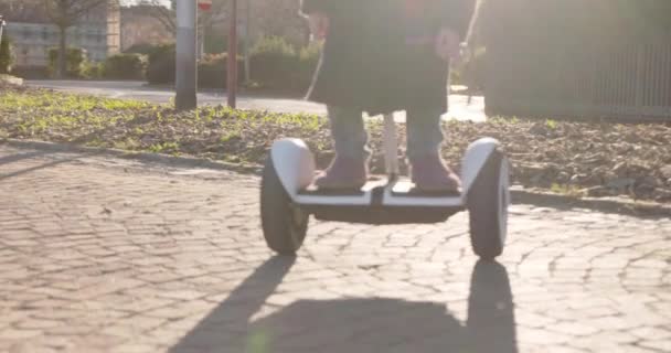 segway detail with daughter child and dad riding.Modern future transport technology.Active Family.Park sidewalk urban outdoor.Warm sunset cold weather backlight.4k slow motion 60p video - Felvétel, videó