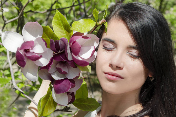 暖かい晴れた日に咲くマグノリア庭で美しい少女 - 写真・画像