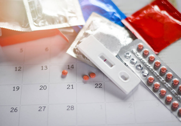 Pilule contraceptive et tests de grossesse Prévenir la grossesse Concept de contraception / Contrôle des naissances avec préservatif sur fond de calendrier - soins de santé et médecine
 - Photo, image