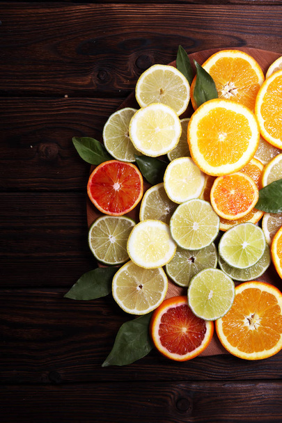 Citrusvruchten met sinaasappel, citroen, grapefruit en limoen op bruine achtergrond. - Foto, afbeelding