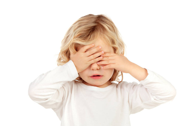 trauriges blondes Kind, das das Gesicht mit den Händen auf weißem Hintergrund verdeckt - Foto, Bild