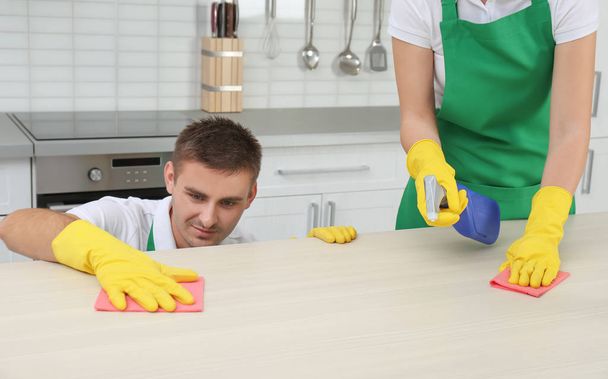 Αρσενικό θυρωρών που καθαρίζουν έπιπλα κουζίνας με πανί στο σπίτι - Φωτογραφία, εικόνα