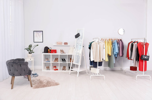 Wardrobe racks with different stylish clothes in light room - Foto, Imagen