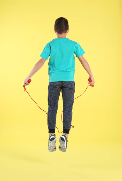 Active boy jumping rope on color background - Zdjęcie, obraz