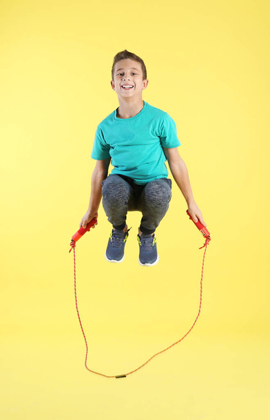 Full length portrait of boy jumping rope on color background - Zdjęcie, obraz