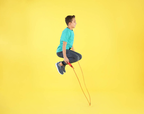 Active boy jumping rope on color background - Valokuva, kuva
