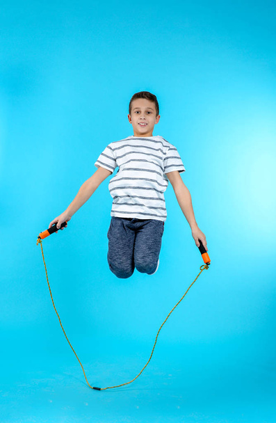 Full length portrait of boy jumping rope on color background - Foto, Bild