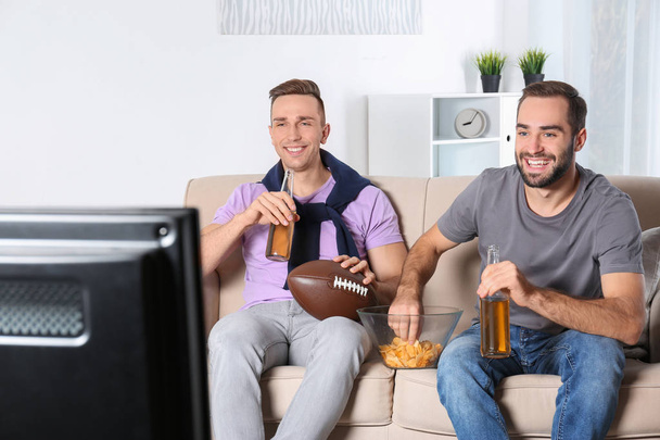 Jovens amigos assistindo TV no sofá em casa. Canal desportivo
 - Foto, Imagem