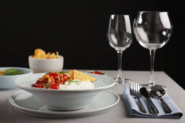 Tasty chili con carne served with rice on gray table. Dinner in restaurant - Фото, изображение