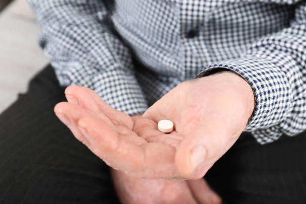 Senior man holding pill in hand, closeup - Photo, Image