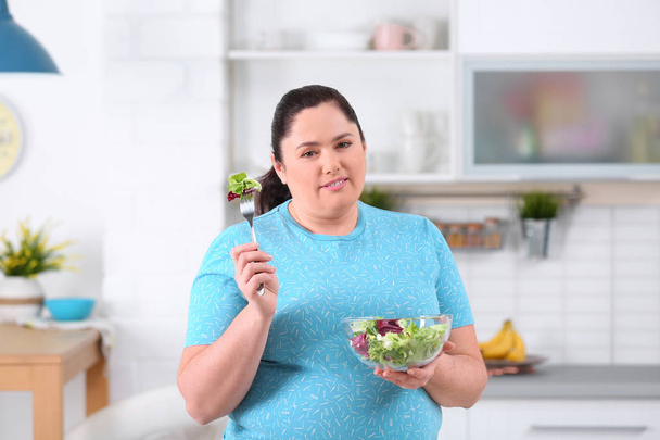 Overweight woman with bowl of salad in kitchen. Healthy diet - Fotó, kép