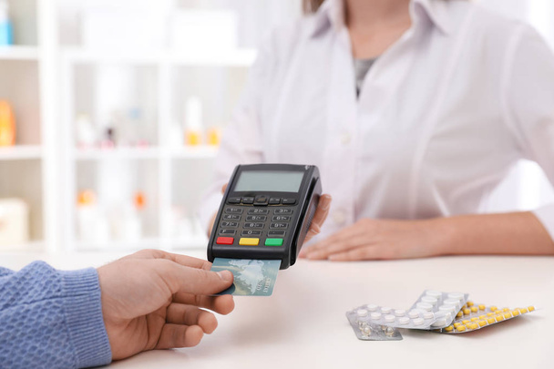 Cliente con carta di credito per il pagamento terminale in farmacia, primo piano
 - Foto, immagini