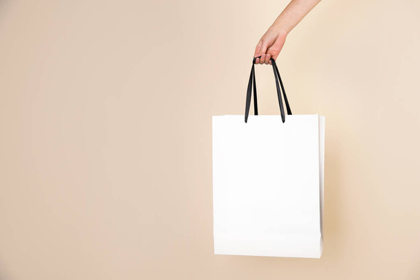 Woman holding paper shopping bag on color background. Mock up for design - Фото, изображение
