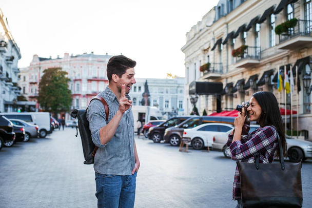 Young mixed race tourist couple taking pictures on vintage camera while walking through the city - Foto, imagen