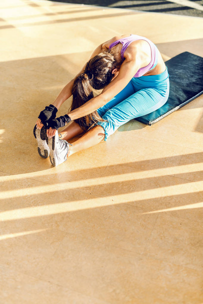 Pohled shora vyhrazené ženy s culíkem na sobě sportovní oblečení na podlaze. Interiér tělocvičny. - Fotografie, Obrázek