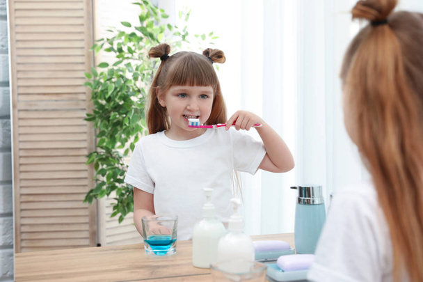 Little girl brushing teeth in bathroom at home - Foto, imagen
