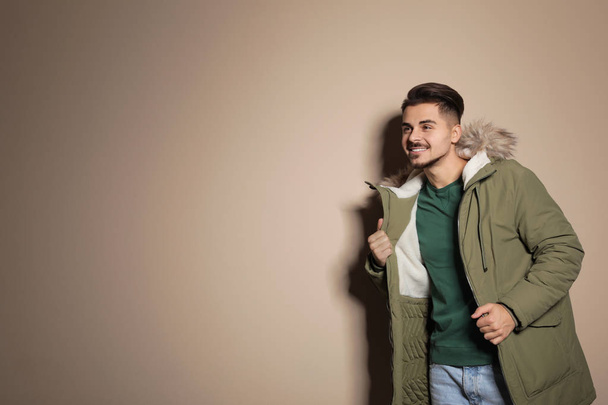 Young man wearing warm clothes on color background, space for text. Ready for winter vacation - Fotoğraf, Görsel