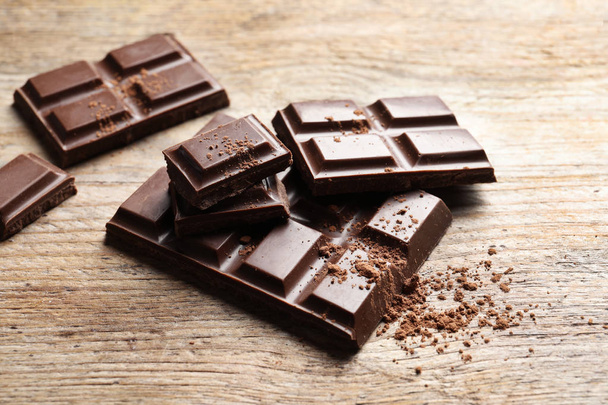 Pieces of tasty chocolate on wooden background - Foto, Bild