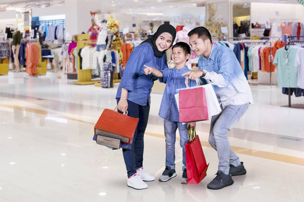 Picture of happy little boy pointing something while shopping with his parents in the mall - 写真・画像