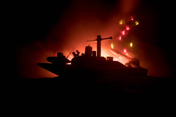 海の戦いのシーン。暗い霧の中での軍事戦争船のシルエットを背景に空のトーン。爆発と装飾としての火災と劇的な戦争シーン。選択的焦点 - 写真・画像