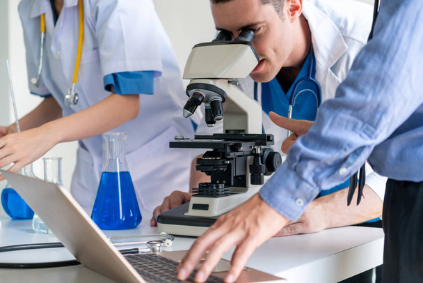 Group of scientists wearing lab coat working in laboratory while examining biochemistry sample in test tube and scientific instruments. Science technology research and development study concept. - Photo, Image