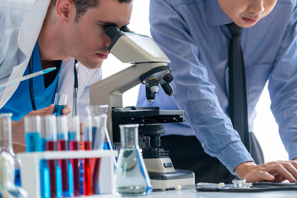 Група вчених, які носять лабораторне пальто, працює в лабораторії, вивчаючи зразки біохімії в пробірці і наукових інструментах. Наукові технології дослідження та розробки концепція дослідження
. - Фото, зображення
