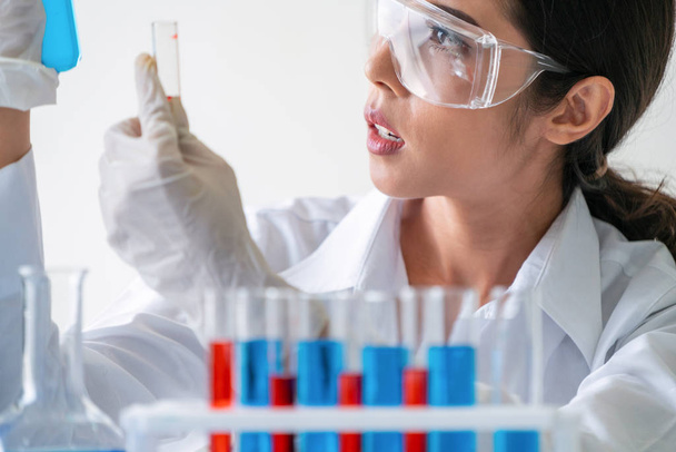 Női tudós, aki laborban dolgozik és biokémiai mintát vizsgál kémcsőben. Tudományos technológiai kutatási és fejlesztési tanulmányi koncepció. - Fotó, kép