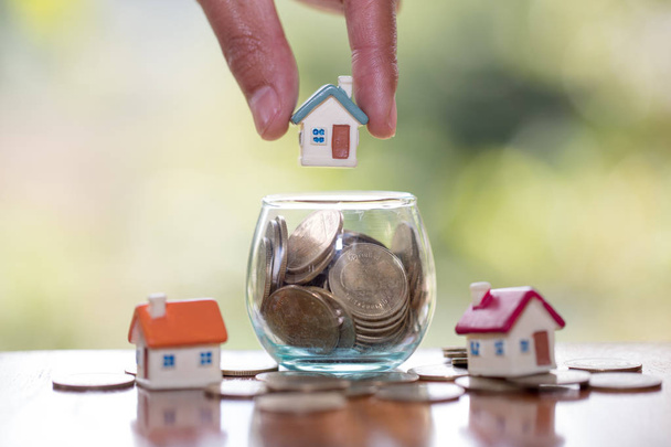 Human hand putting house model on coins stack,  planning savings money of coins to buy a home concept, mortgage and real estate investment.  saving or investment for a house. - Foto, afbeelding