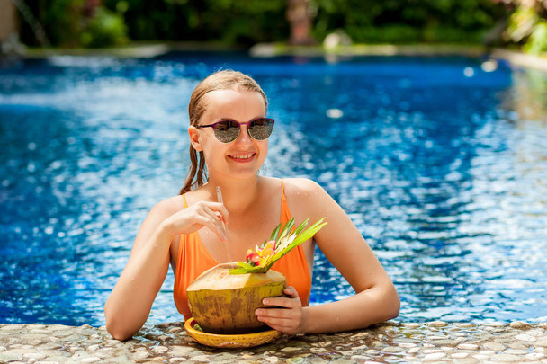 Girl with coconut in the pool with sunglasses - Foto, immagini