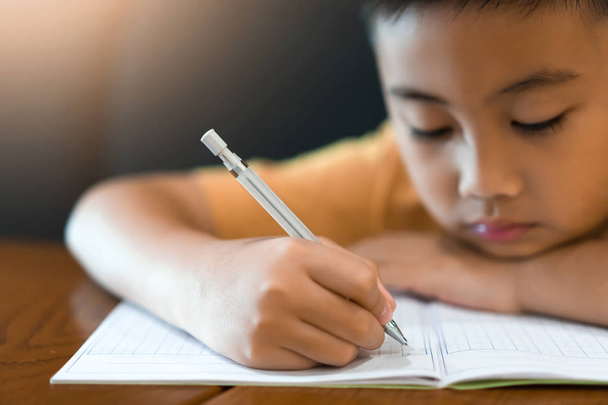 Μικρό αγόρι χέρι γράφει την εργασία στο σπίτι. Έννοια της εκπαίδευσης - Φωτογραφία, εικόνα