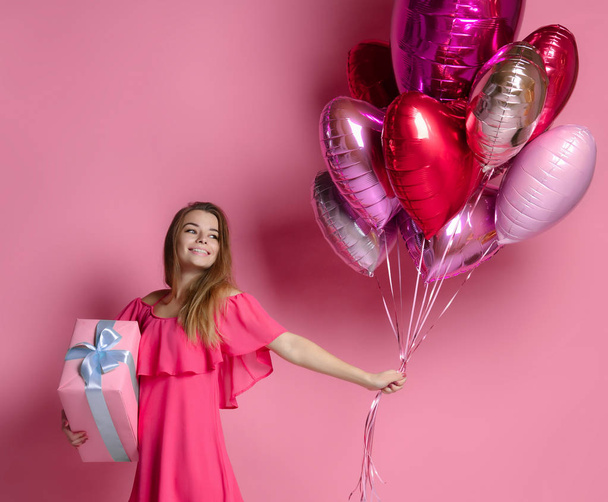 Valentine Beauty girl hold red and pink air balloons laughing on pink background celebrating Valentines Day - Zdjęcie, obraz