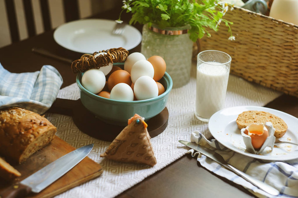 country breakfast on rustic home kitchen with farm eggs, butter, wholegrain bread and milk. Organic homemade food, easter concept.   - Foto, immagini