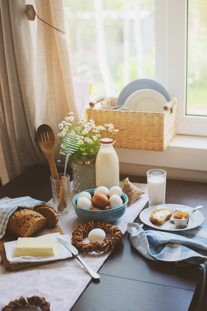 country breakfast on rustic home kitchen with farm eggs, butter, wholegrain bread and milk. Organic homemade food, easter concept.   - Fotografie, Obrázek