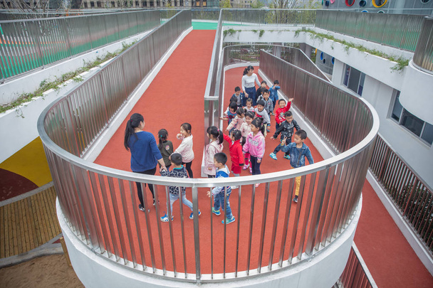 Chinese children walk towards running tracks on the rooftop of a building at a newly-opened kindergarten in Huzhou, east China's Zhejiang province, 17 October 2016 - Photo, Image