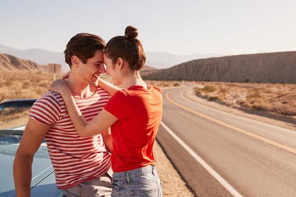 Young couple embracing by their car at the roadside - Foto, Imagen