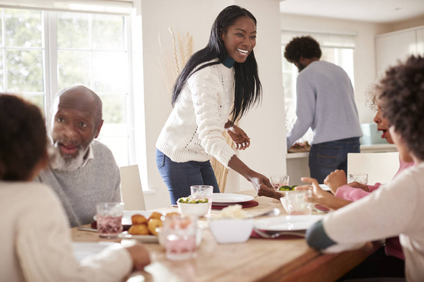 Black couple bringing food to the table for Sunday family dinner for the kids and grandparents - Фото, изображение