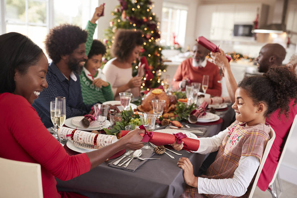 Mixed race, multi-generation family having fun pulling crackers at the Christmas dinner table - Foto, Imagem