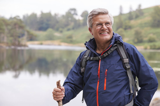 Middle aged man standing at lake in forest and smiling  - Fotoğraf, Görsel