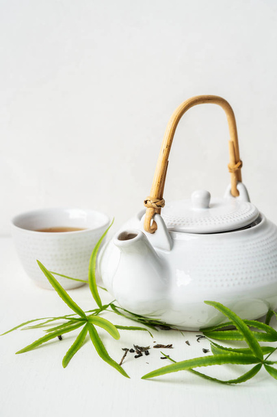 Asian set with green tea, cup and teapot on white background with green leaves  - Fotoğraf, Görsel