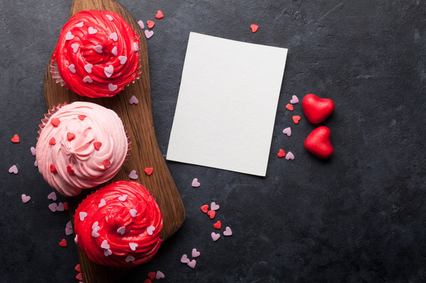 Tarjeta de felicitación del día de San Valentín con deliciosos cupcakes dulces sobre fondo de piedra
 - Foto, Imagen