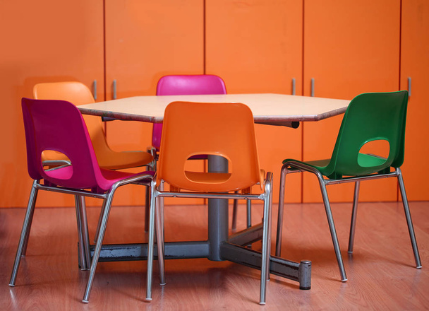 dentro de un aula escolar de un jardín de infantes con sillas pequeñas y una mesa hexagonal sin los niños
 - Foto, Imagen