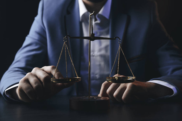 pojęcie prawa i sprawiedliwości. Mężczyzna prawnika w biurze z mosiądzu skali na drewnianym stole, odzwierciedlenie - Zdjęcie, obraz