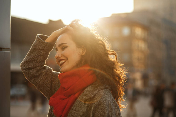 Retrato de primavera de la alegre modelo joven con el pelo ondulado con abrigo de gran tamaño y bufanda roja. Espacio vacío
 - Foto, imagen