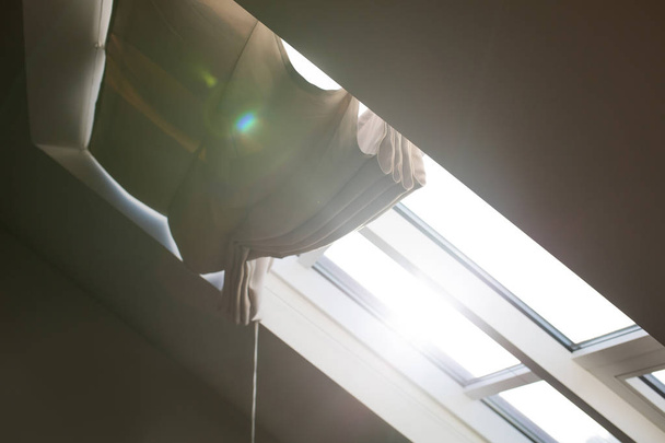 Moderna ventana de mansarda con persianas en una habitación del ático con luz solar y deslumbramiento
 - Foto, Imagen