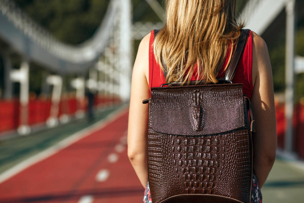 Young woman traveler with a leather backpack posing at the bridge in sunny day. Space for text - Fotoğraf, Görsel