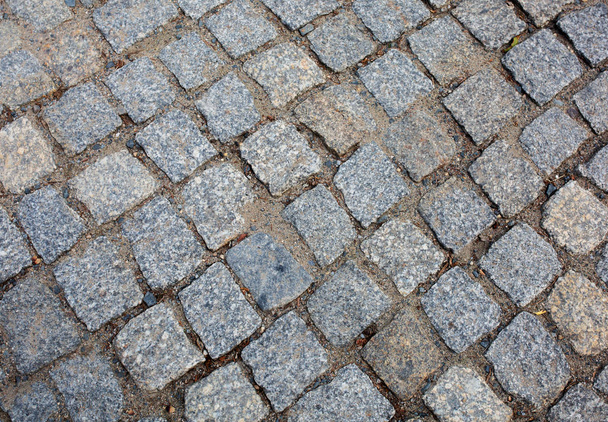 Old pedestrian road paved with granite stones. Closeup shot - Photo, Image